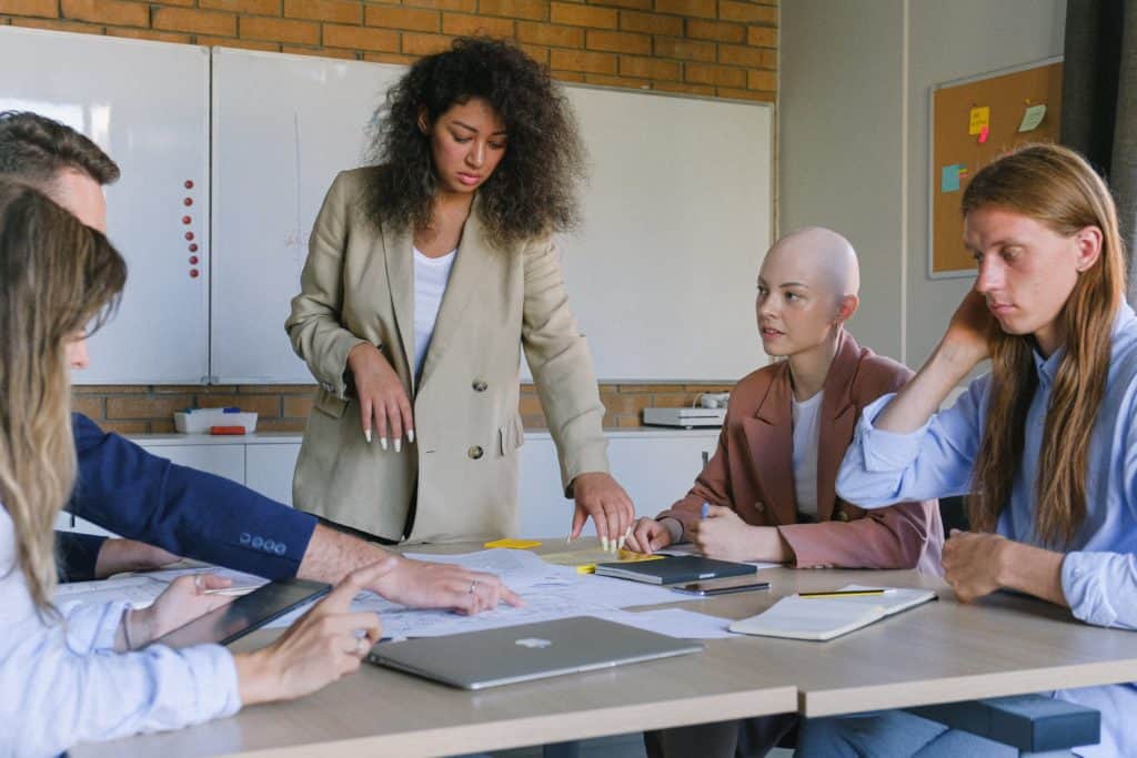 A group of people sitting at a table discussing work things.
