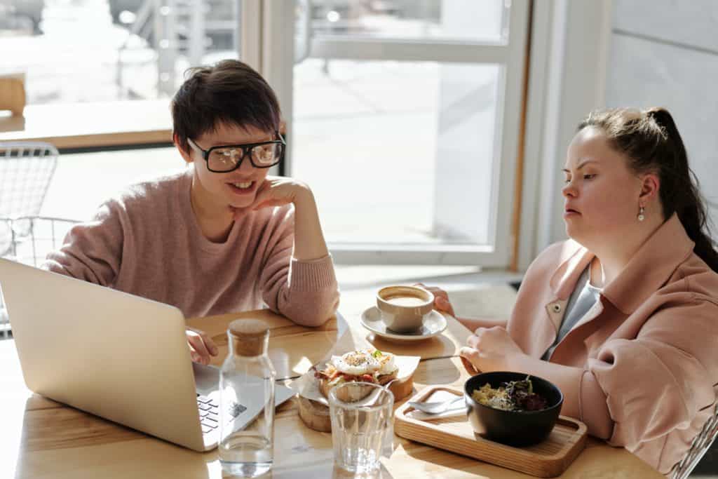 The Benefits Behind Understanding How Microsoft 365 Works 1 two people looking at a computer and eating food. The computer may have Microsoft 365 on it.